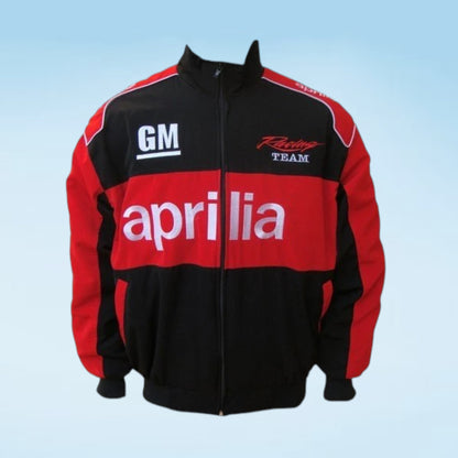 A red and black zip-up jacket with 'Aprilia' in white across the chest, 'GM' on the right chest, and 'Racing Team' on the left chest, shown against a light blue gradient background.