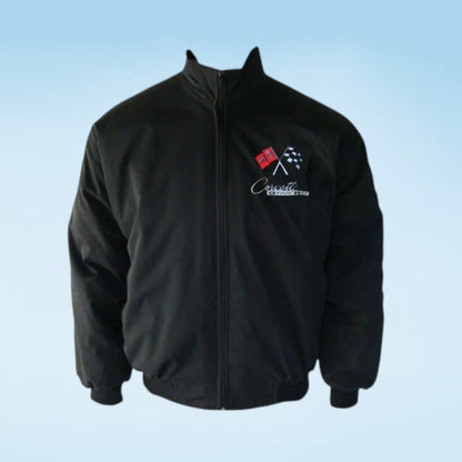 A black zip-up jacket with a stand collar, ribbed cuffs and hem, featuring a white script logo and crossed checkered flags on the left chest, displayed against a light blue gradient background.