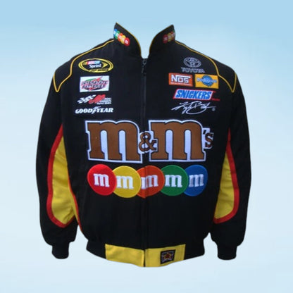 A black zip-up racing-style jacket with large M&M's branding across the front, plus sponsor logos including Goodyear, NOS, and Snickers, shown on a light blue gradient background.