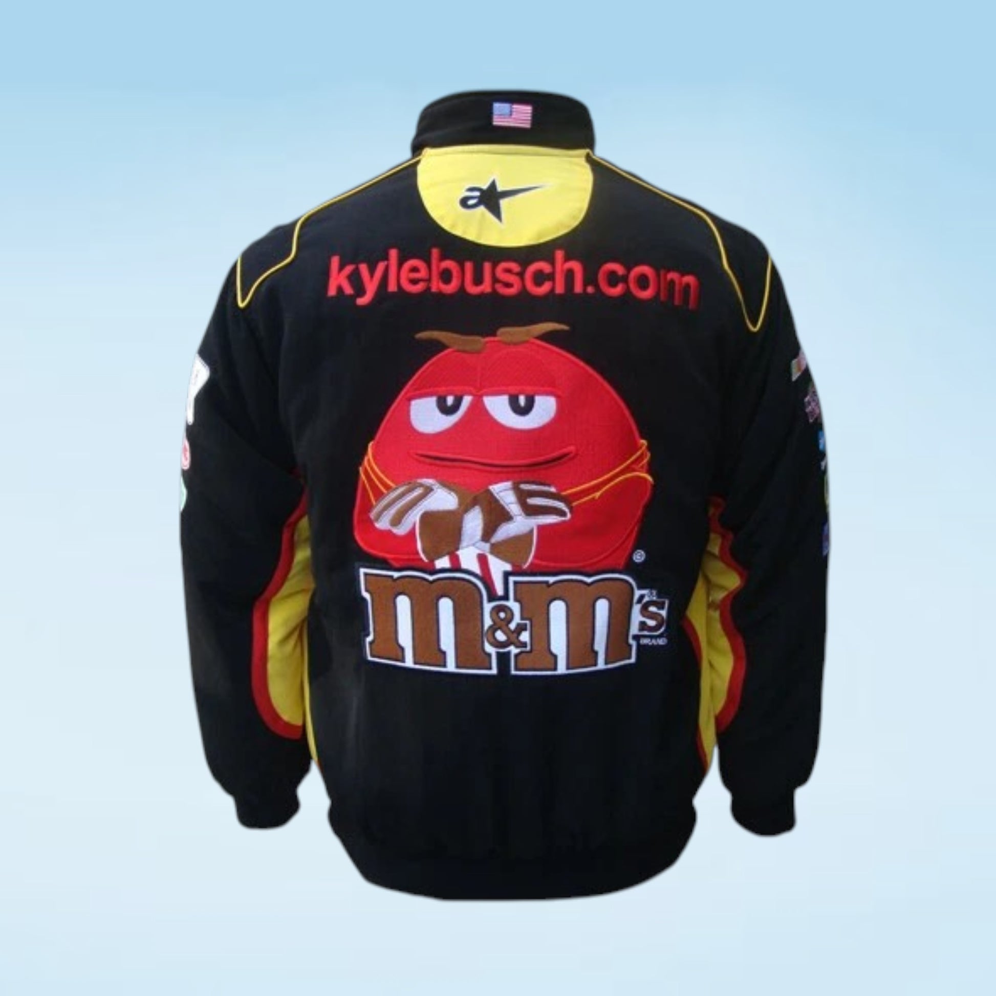 A black racing-style jacket shown from the back, featuring a large red M&M's character graphic with 'm&m's' text, 'kylebusch.com' across the upper back, and a yellow M&M's patch near the collar.