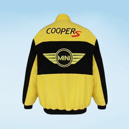 A yellow and black Cooper S Mini jacket shown from the back, featuring the 'COOPER S' logo in black and red on the upper back and the circular 'MINI' winged emblem in yellow on the lower back, set against a light blue gradient background.